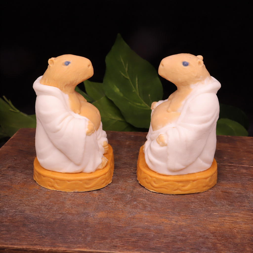 Handmade Goat Milk Budda Capybara soaps sitting on a wooden box facing each other. 