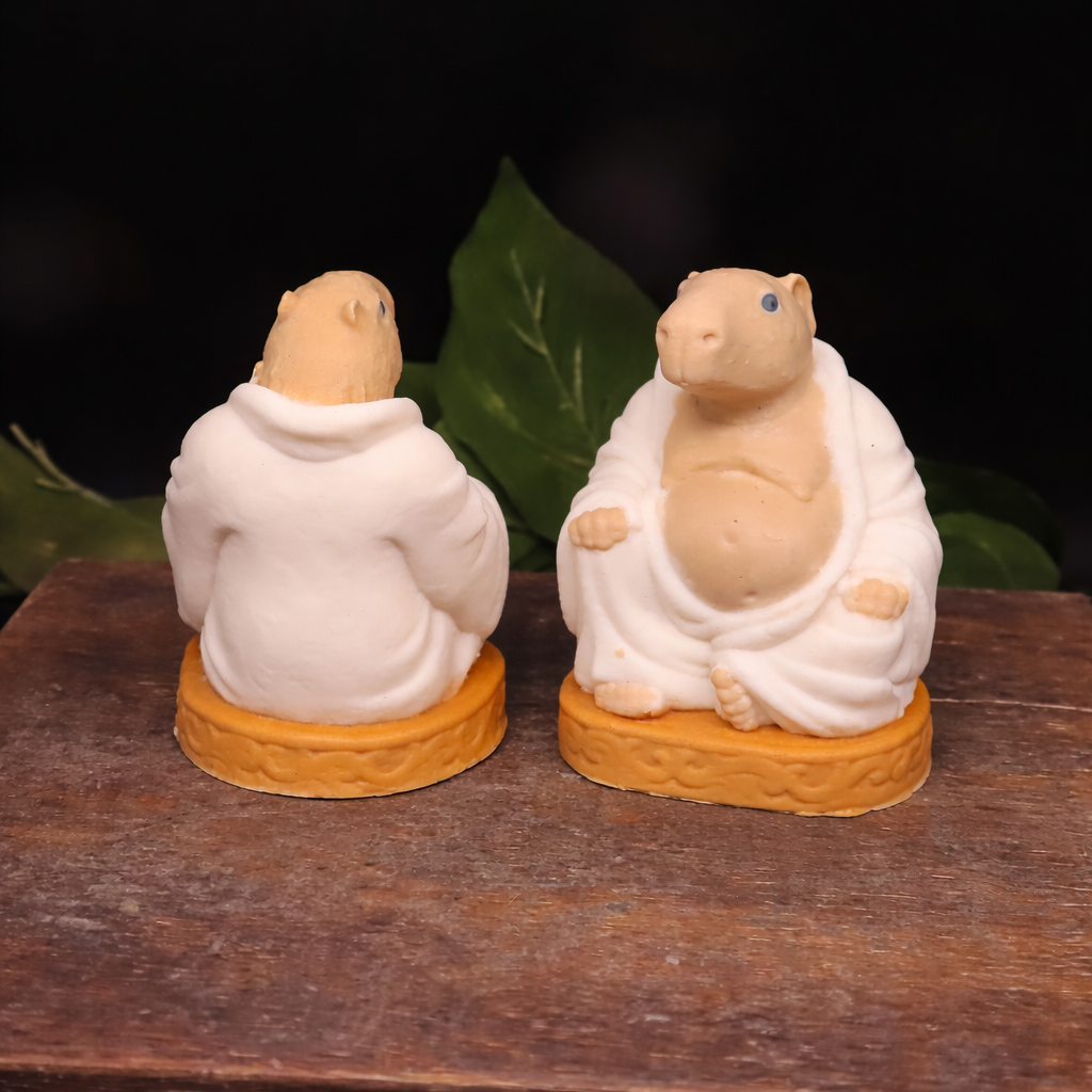 Handmade Goat Milk Budda Capybara soaps sitting on awooden box.  One facing forward, the other  facing backward