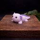 Individually handcrafted purple axolotl goat milk  soap keepsake styled on a rustic wooden block with warm lighting and dark background