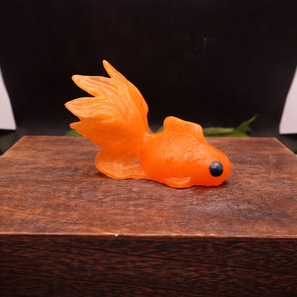 Orange fish-shaped glycerin soap bar, handmade novelty soap photographed from side angle on wooden surface.

Alt Text Option 3