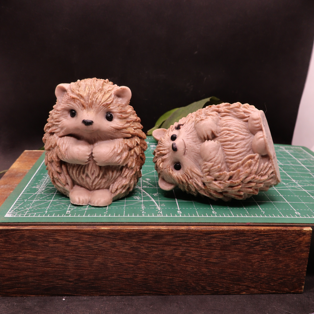 Two large handmade hedgehog goat milk soaps photographed on a cutting mat for accurate size reference and scale comparison.